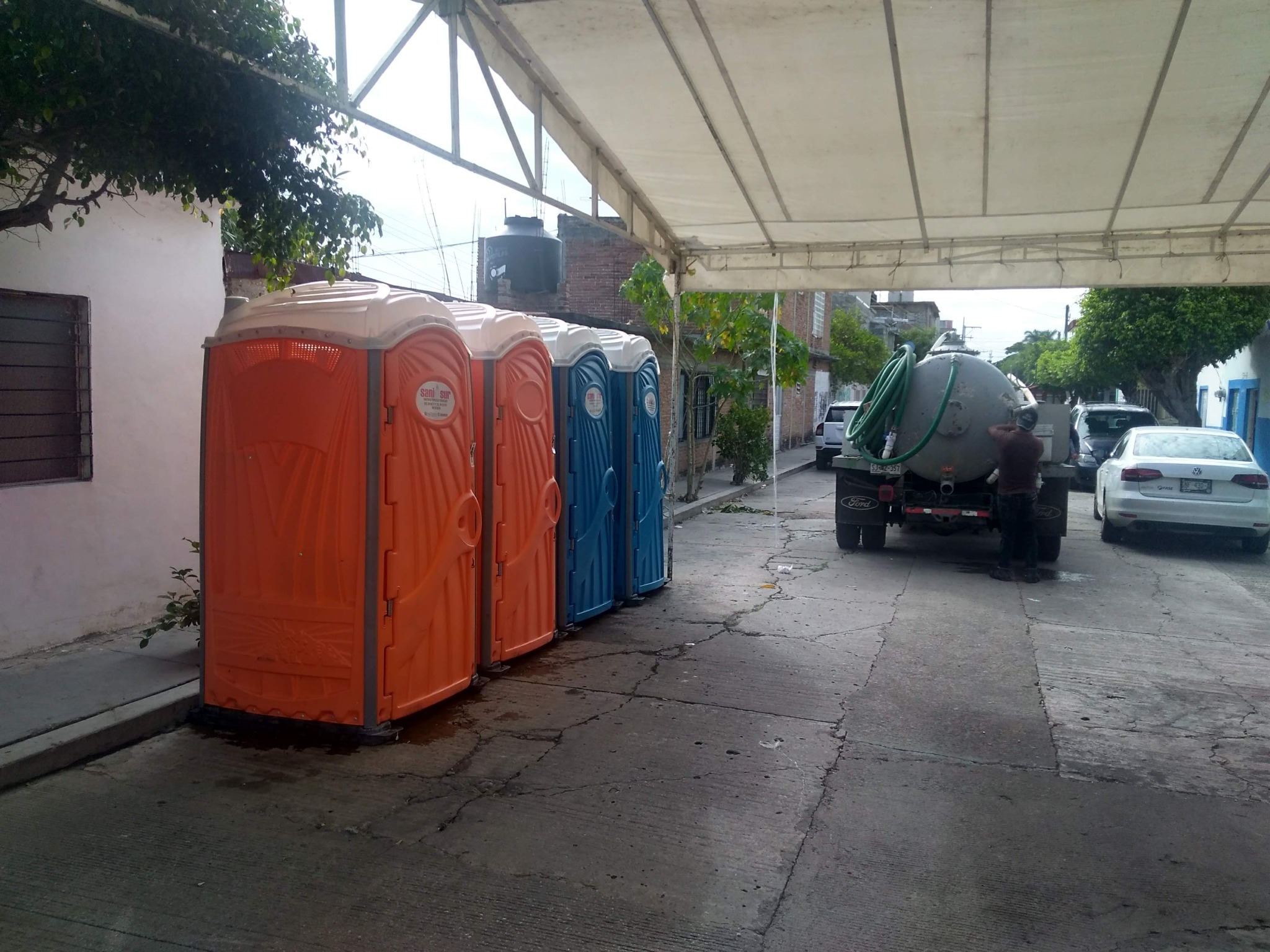 Fila de baños portátiles con unidad de servicio al fondo
